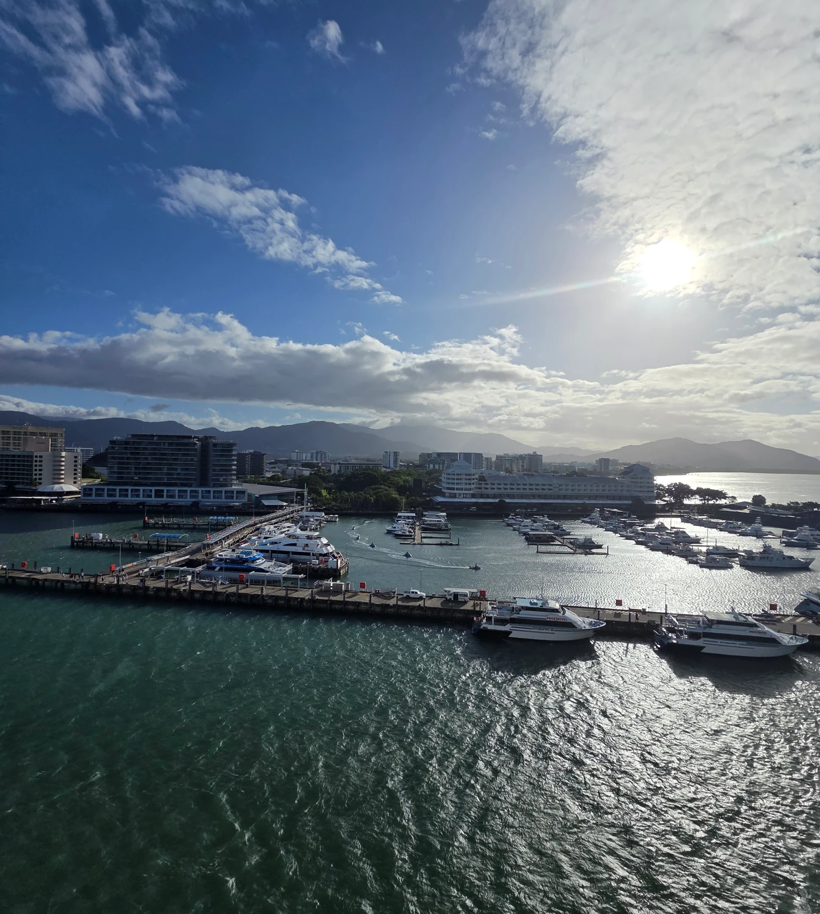 Boats at the Cairns marina with the city and tropical ranges beyond