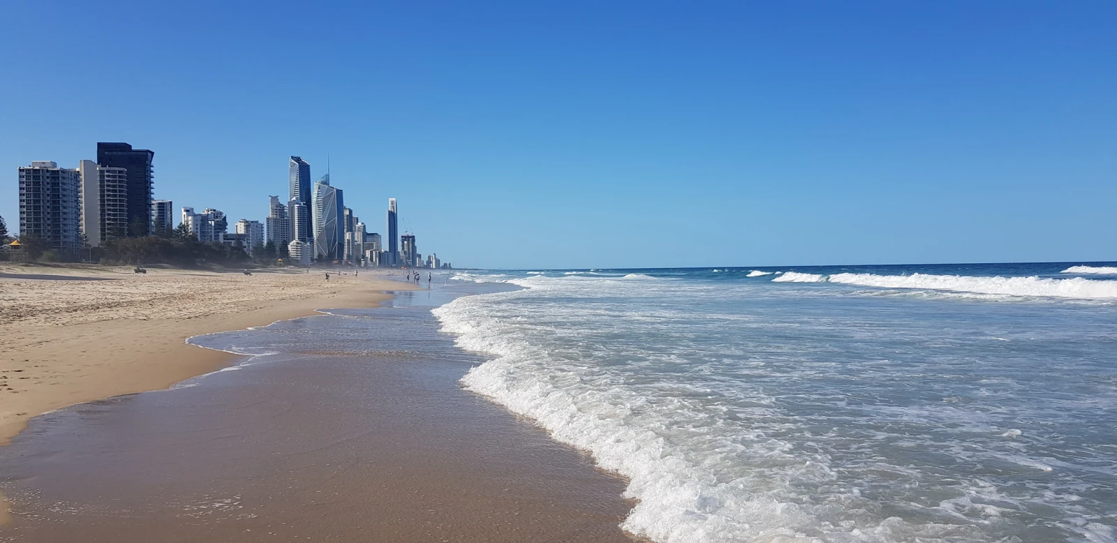 Gold Coast beachfront, city skyline and breaking surf beneath a blue sky